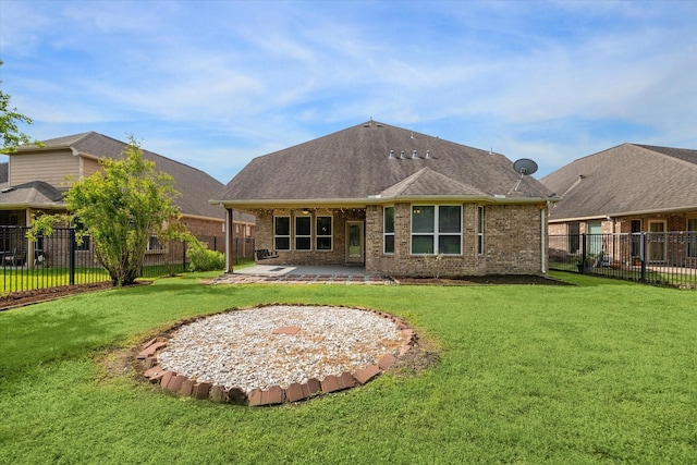 back of house featuring roof with shingles, a fenced backyard, brick siding, a yard, and a patio
