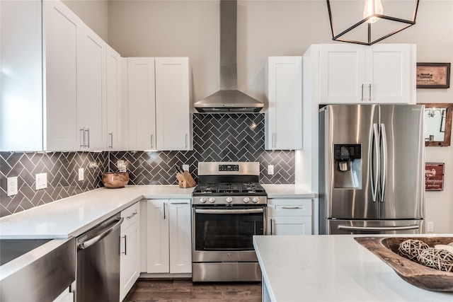 kitchen with appliances with stainless steel finishes, wall chimney range hood, and white cabinetry