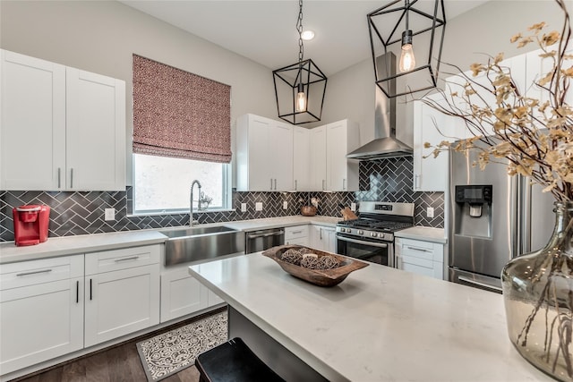 kitchen featuring stainless steel appliances, a sink, white cabinets, decorative backsplash, and decorative light fixtures