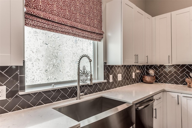 kitchen with backsplash, a sink, dishwasher, and white cabinetry