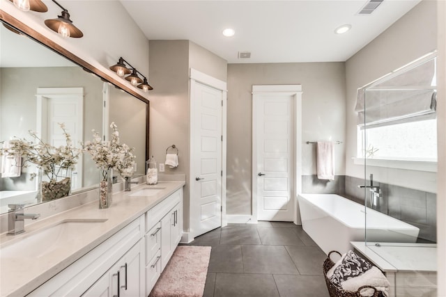 full bath with a freestanding tub, tile patterned flooring, double vanity, and recessed lighting