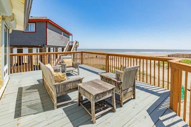 deck featuring view of water and beach and outdoor lounge area