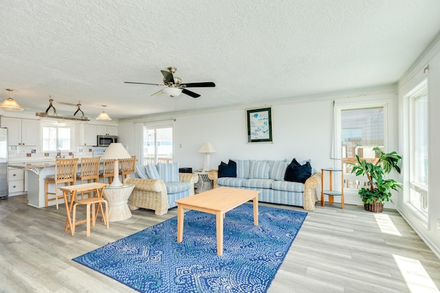 living room featuring a textured ceiling, light wood finished floors, and a ceiling fan