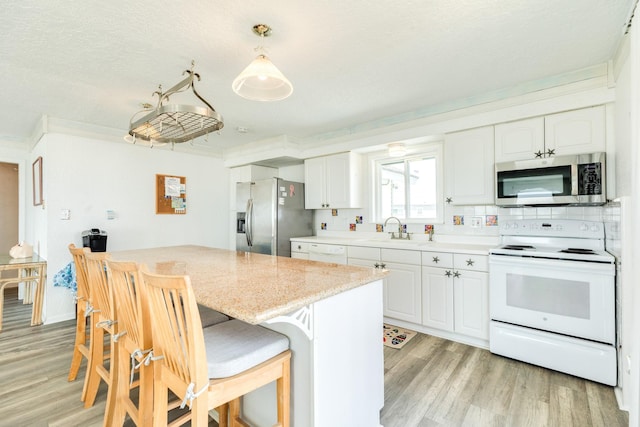 kitchen featuring stainless steel appliances, light wood finished floors, and white cabinetry