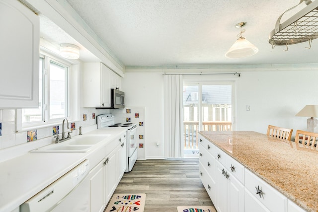 kitchen featuring white appliances, a sink, white cabinets, light wood finished floors, and a textured ceiling