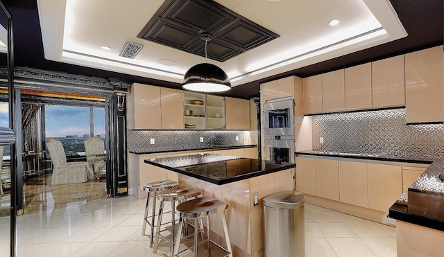 101 Westcott St Unit 2001, Houston, TX 77007 - kitchen featuring visible vents, a center island, dark countertops, a tray ceiling, and light tile patterned flooring