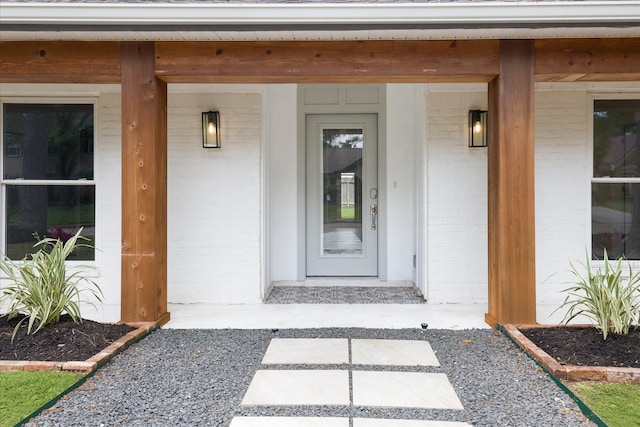 view of exterior entry with covered porch and brick siding