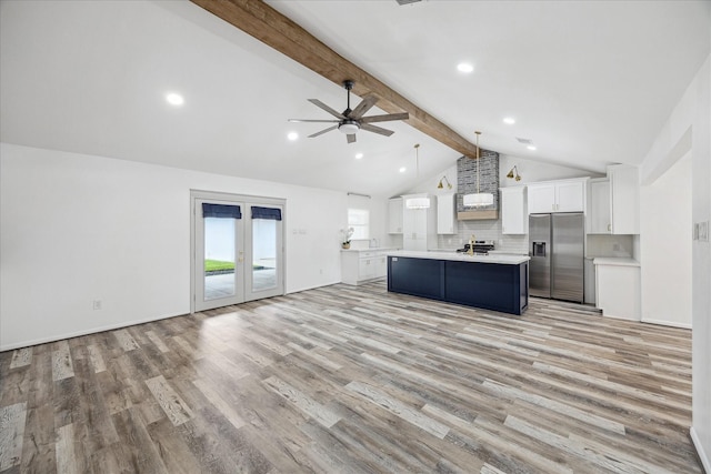 kitchen with beam ceiling, stainless steel fridge, light countertops, white cabinets, and open floor plan