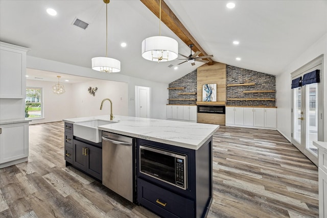 kitchen featuring vaulted ceiling with beams, open floor plan, appliances with stainless steel finishes, and a sink