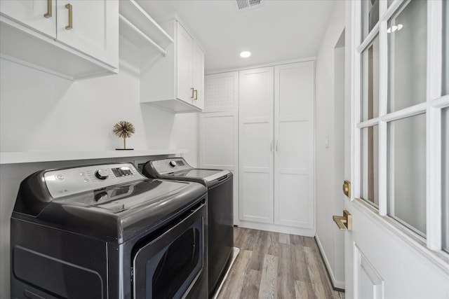 washroom featuring light wood-style flooring, separate washer and dryer, cabinet space, and recessed lighting