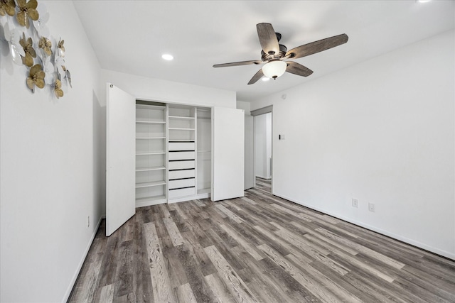 unfurnished bedroom with recessed lighting, a closet, a ceiling fan, baseboards, and wood finished floors