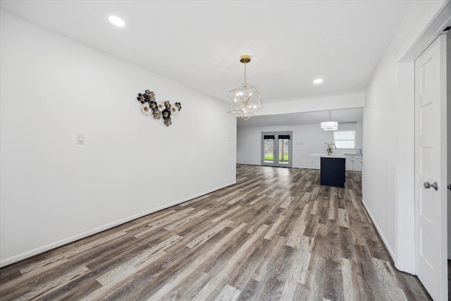 unfurnished living room featuring recessed lighting, baseboards, a chandelier, and dark wood-type flooring