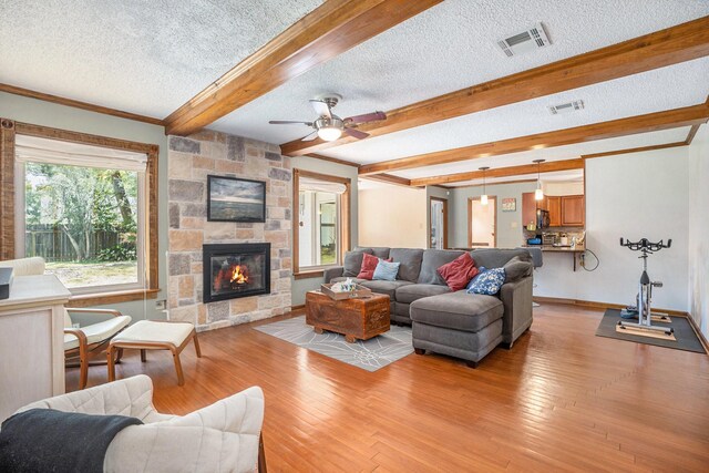 living area with beamed ceiling, a textured ceiling, baseboards, and visible vents