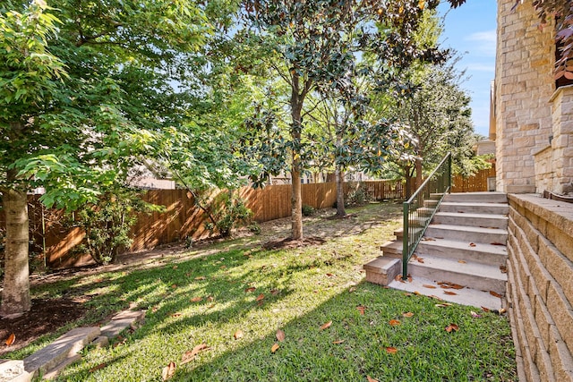 view of yard featuring a fenced backyard and stairs