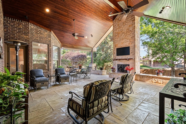 view of patio / terrace with fence, a ceiling fan, outdoor dining area, and an outdoor living space with a fireplace