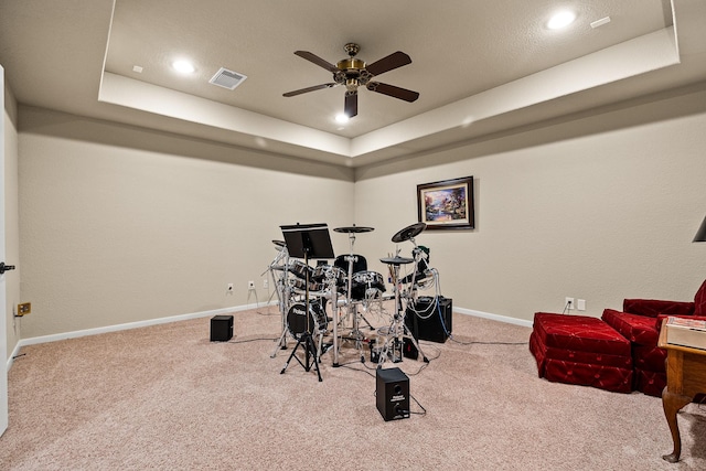 game room with visible vents, a ceiling fan, carpet, and a tray ceiling