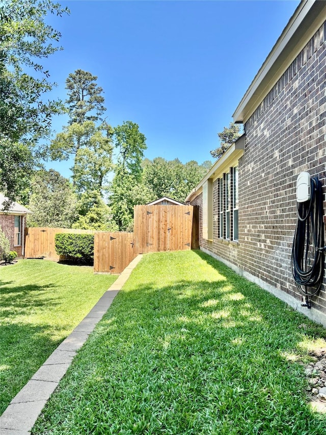 view of yard featuring a fenced backyard, a gate, and a shed