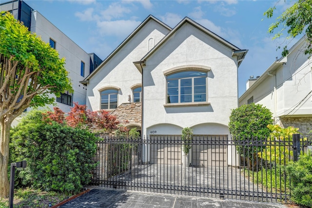 609 Reinicke St, Houston, TX 77007 - french country style house featuring a garage, stucco siding, and a fenced front yard
