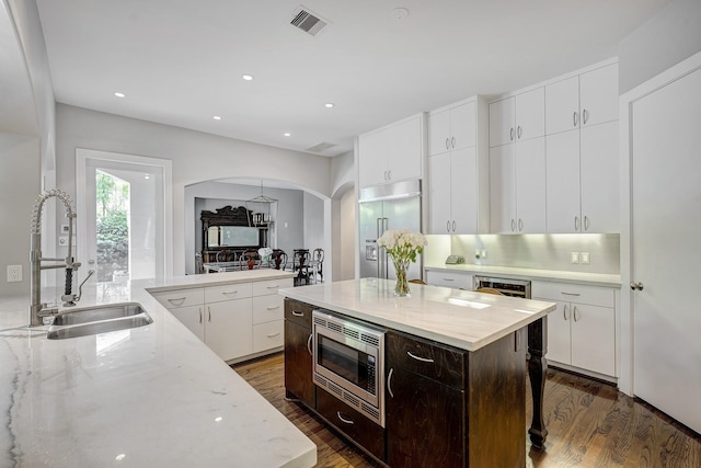 609 Reinicke St, Houston, TX 77007 - kitchen with arched walkways, visible vents, a sink, built in appliances, and dark wood-style floors