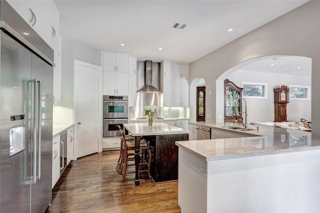 609 Reinicke St, Houston, TX 77007 - kitchen featuring visible vents, a sink, wall chimney range hood, a spacious island, and stainless steel appliances