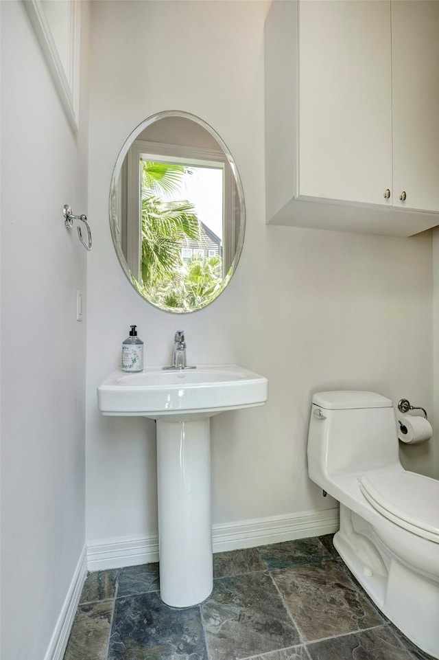 609 Reinicke St, Houston, TX 77007 - bathroom with stone finish flooring, baseboards, and toilet