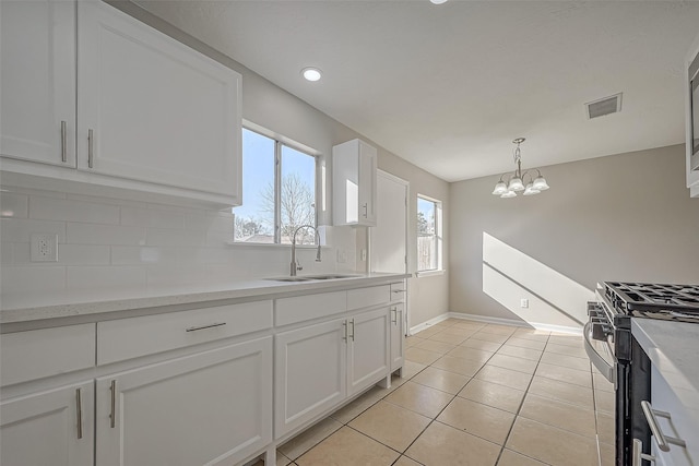 8719 Valley Meadow Dr, Houston, TX 77078 - kitchen featuring tasteful backsplash, visible vents, stainless steel range with gas stovetop, a sink, and white cabinetry