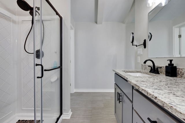 bathroom with a shower stall, wood finished floors, vanity, and baseboards