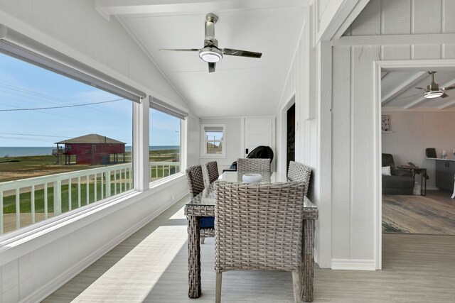 sunroom with vaulted ceiling with beams, a ceiling fan, and wood finished floors