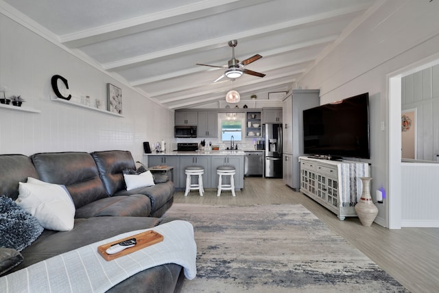 living area featuring light wood finished floors, a ceiling fan, and lofted ceiling with beams
