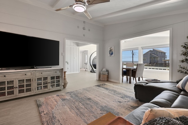 living area with wood finished floors, beam ceiling, and ceiling fan