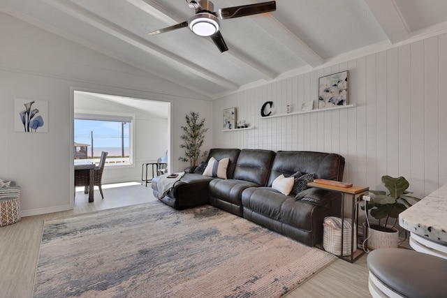 living area featuring ceiling fan, lofted ceiling with beams, wood finished floors, wood walls, and baseboards