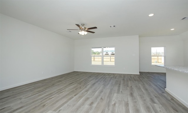 spare room with light wood-style flooring, visible vents, a wealth of natural light, and a ceiling fan