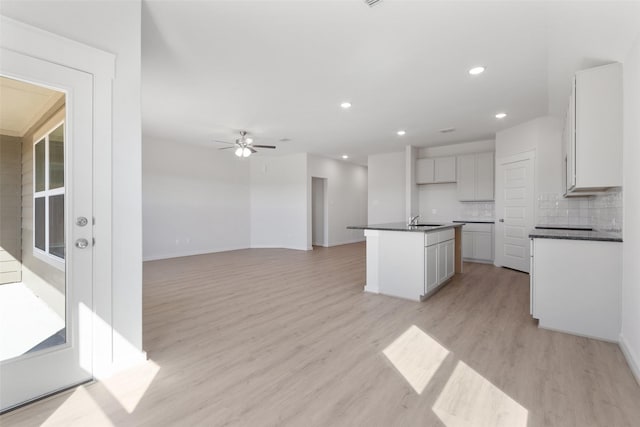 4741 Peony Green Dr, Katy, TX 77493 - kitchen with dark countertops, a sink, light wood-style floors, a center island with sink, and recessed lighting