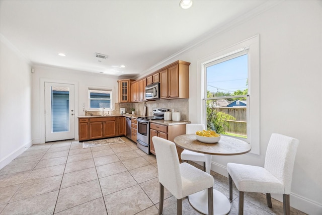 636 Pizer St, Houston, TX 77009 - kitchen with stainless steel appliances, ornamental molding, plenty of natural light, brown cabinets, and recessed lighting
