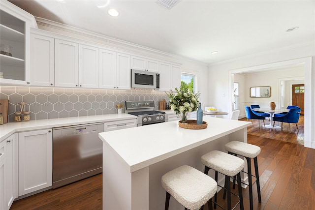 636 Pizer St, Houston, TX 77009 - kitchen featuring appliances with stainless steel finishes, a breakfast bar, white cabinetry, dark wood finished floors, and recessed lighting