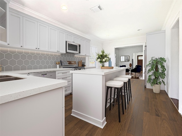 636 Pizer St, Houston, TX 77009 - kitchen featuring appliances with stainless steel finishes, a kitchen bar, light countertops, a center island, and backsplash