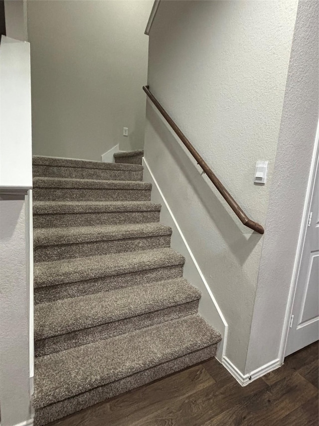 stairway featuring a textured wall, wood finished floors, and baseboards