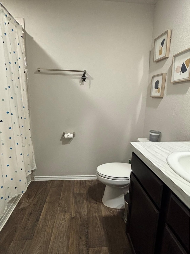 bathroom featuring wood finished floors, toilet, a shower with shower curtain, and vanity