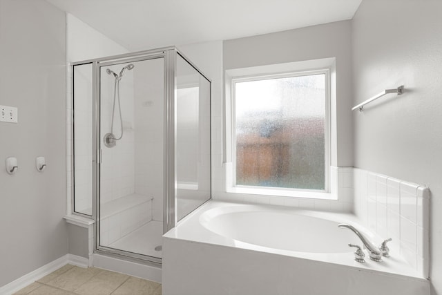 bathroom featuring tile patterned floors, baseboards, a garden tub, and a stall shower