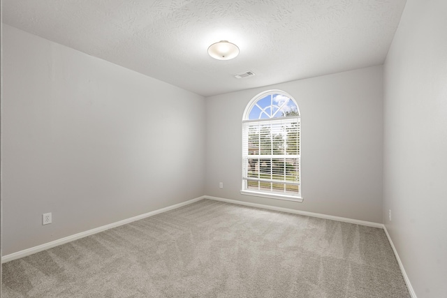 unfurnished room with visible vents, baseboards, carpet floors, and a textured ceiling