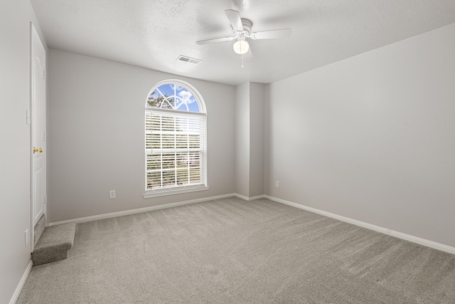 carpeted spare room with visible vents, baseboards, a textured ceiling, and ceiling fan
