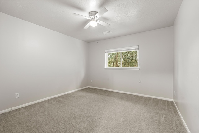 carpeted empty room with a textured ceiling, ceiling fan, baseboards, and visible vents