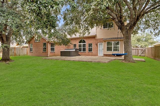 back of property featuring brick siding, a fenced backyard, a patio, and a hot tub
