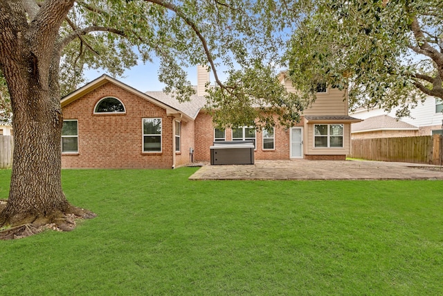rear view of property featuring a hot tub, a yard, a patio, fence, and brick siding