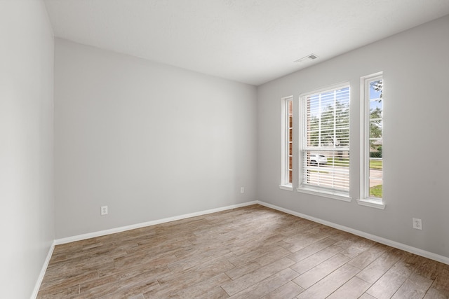 spare room featuring visible vents, baseboards, and wood finished floors
