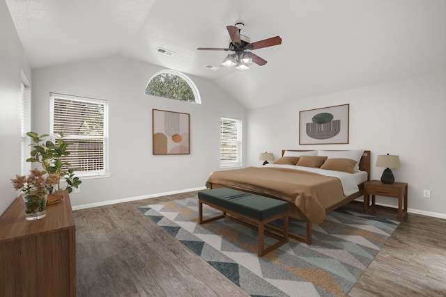 bedroom featuring wood finished floors, baseboards, lofted ceiling, and visible vents