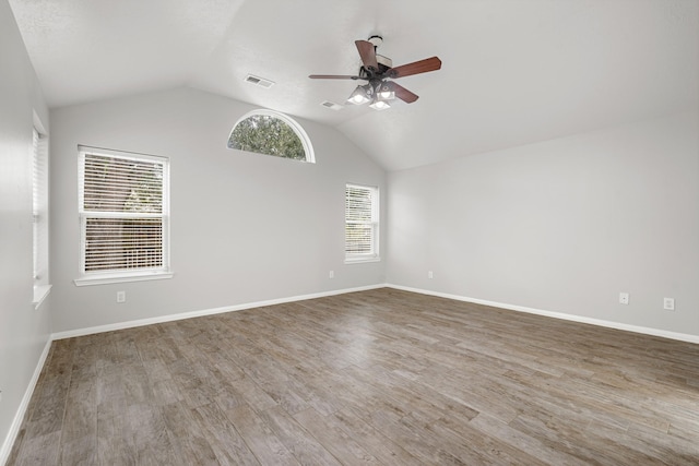 empty room with visible vents, a ceiling fan, wood finished floors, and lofted ceiling