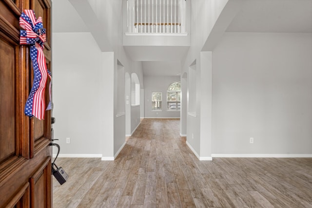 entryway featuring arched walkways, baseboards, and light wood-type flooring
