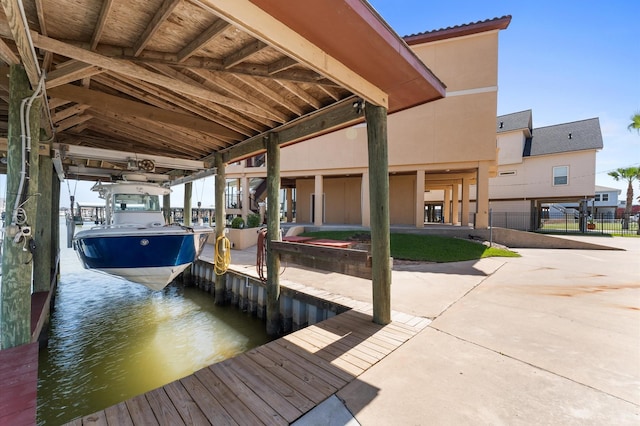 dock area featuring boat lift, fence, and a water view