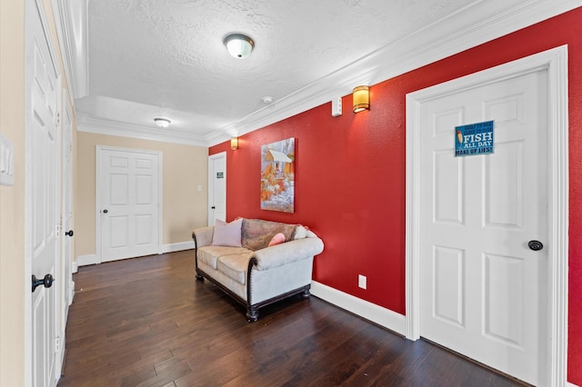 sitting room with a textured ceiling, crown molding, dark wood-style floors, and baseboards